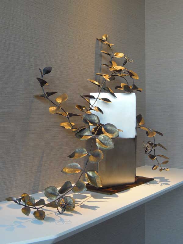 厚みのあるステンレス板の隙間からツルニチニチソウが伸びている様子を鍛鉄で表現したアート作品。花はワイヤーワークになっています。