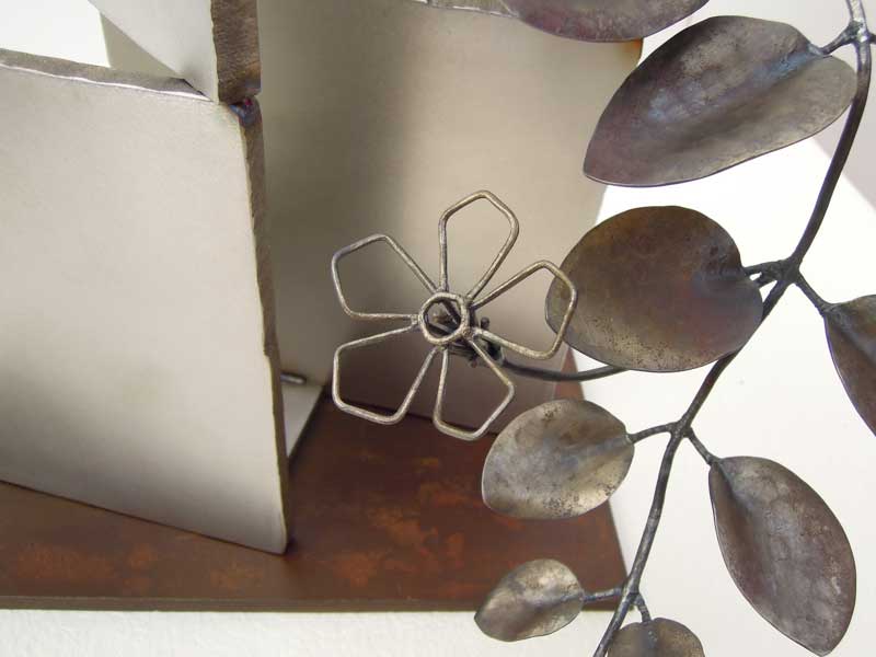 厚みのあるステンレス板の隙間からツルニチニチソウが伸びている様子を鍛鉄で表現したアート作品。花、葉、ベースと、全て金属でありながらそれぞれに個性的な仕上げとなっている様子がわかります。