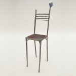 鉄で出来ている椅子のオブジェ。スタイリッシュなハイバックデザイン。卓上サイズながら繊細に作りこまれたディテール。トップに小さな翼が付いています。斜めからの写真。