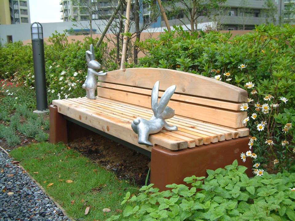 マンション中庭に設置になったうさぎの彫刻作品。ベンチによじ登るウサギと、背もたれに立つウサギ