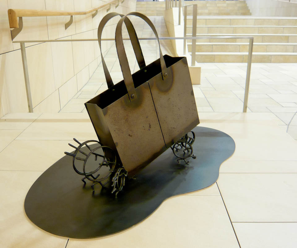 横浜ノースポートモールにオープン時設置されていたアートオブジェ「急ぐヤツら」。忘れ物のバッグや鞄を届けるために駅へと急いでいる彫刻作品です。全て鉄で制作されました。トートバッグを運ぶ作品。