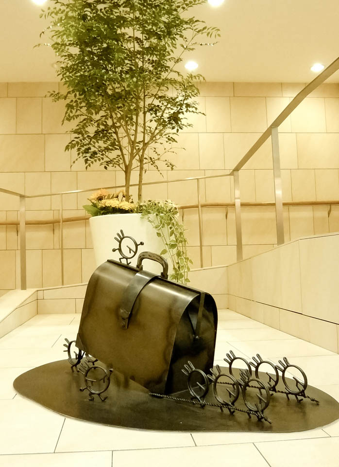 横浜ノースポートモールにオープン時設置されていたアートオブジェ「急ぐヤツら」。忘れ物のバッグや鞄を届けるために駅へと急いでいる彫刻作品です。全て鉄で制作されました。ドクターバッグを運ぶ作品。