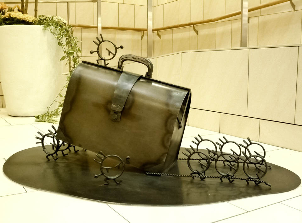 横浜ノースポートモールにオープン時設置されていたアートオブジェ「急ぐヤツら」。忘れ物のバッグや鞄を届けるために駅へと急いでいる彫刻作品です。全て鉄で制作されました。ドクターバッグを運ぶ作品。