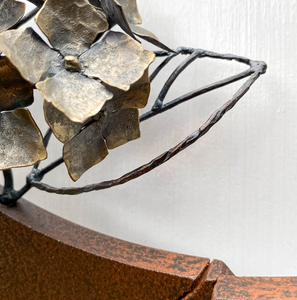 紫陽花のこんもりした花が円の中に添えられているアート作品、鉄の彫刻です。 柔らかい花びらを模した鉄のアジサイの花に、面と線で表現した葉が寄り添っています。 線の葉の表情。