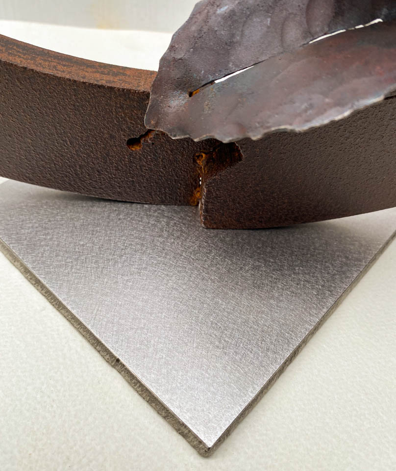 紫陽花のこんもりした花が円の中に添えられているアート作品、鉄の彫刻です。柔らかい花びらを模した鉄のアジサイの花に、面と線で表現した葉が寄り添っています。ベースの仕上げの表情。