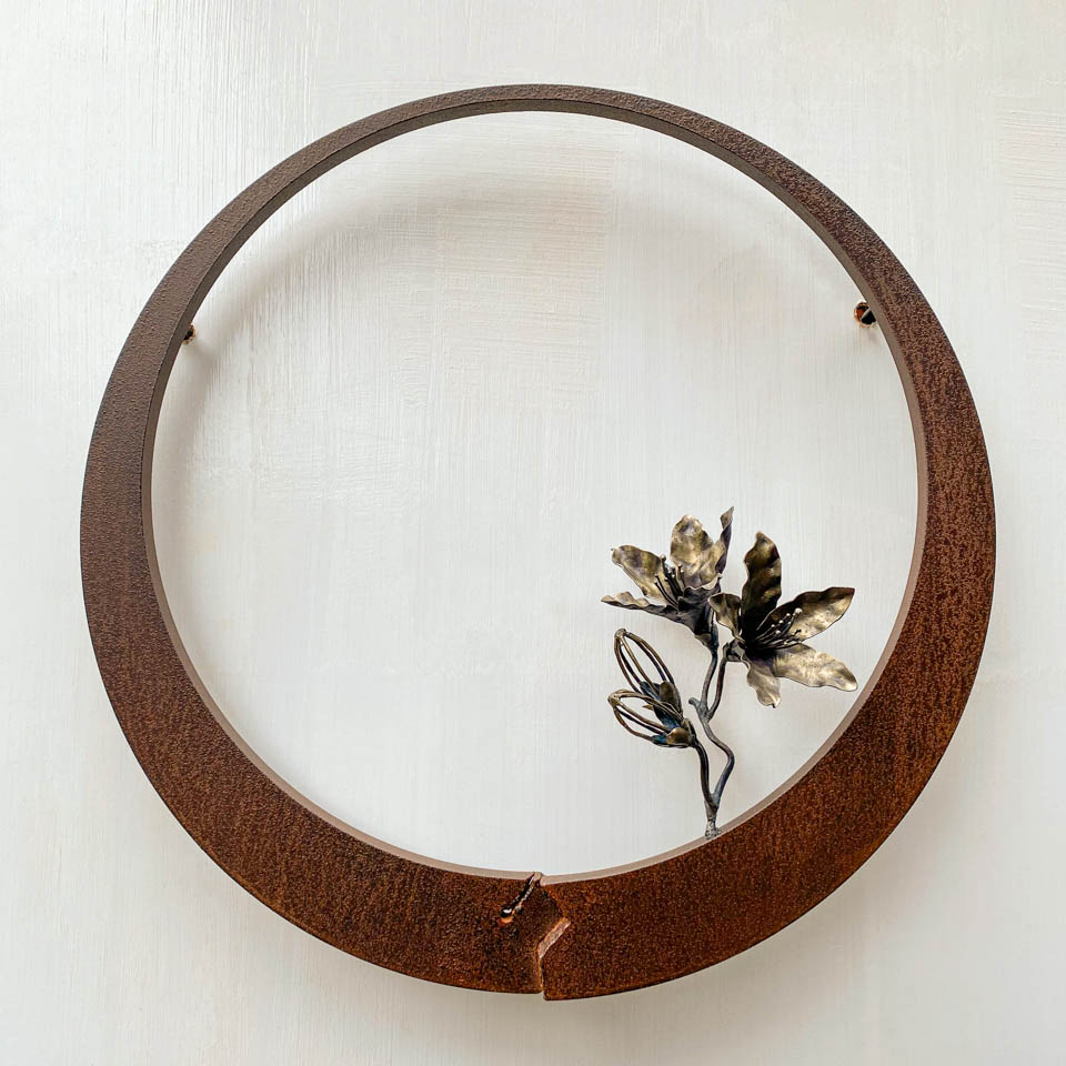 箱根の春を彩るミツバツツジの花を円弧に添えた鉄の彫刻、アート作品です。壁面へ取り付ける仕様になっています。蕾は鍛造した鉄線で表現し軽い印象になっています。円弧は厚みのある鉄を切り出し、下部でズラして表情をつけています。