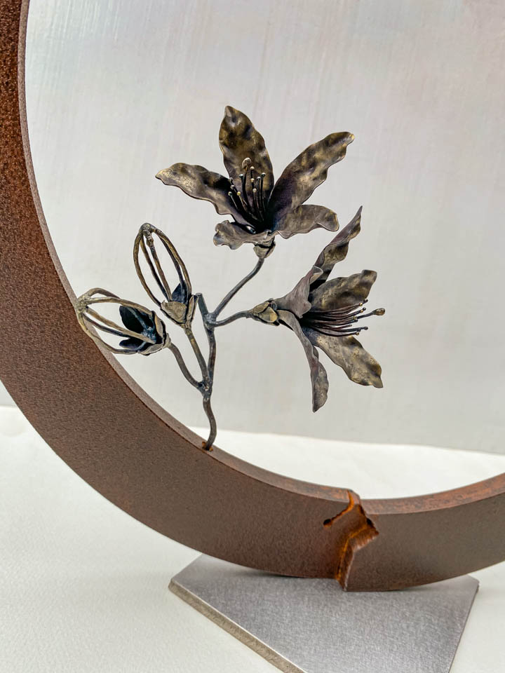 箱根の春を彩るミツバツツジの花を円弧に添えた鉄の彫刻、アート作品です。スタンドタイプです。蕾は鍛造した鉄線で表現し軽い印象になっています。円弧は厚みのある鉄を切り出し、下部でズラして表情をつけています。花の様子。