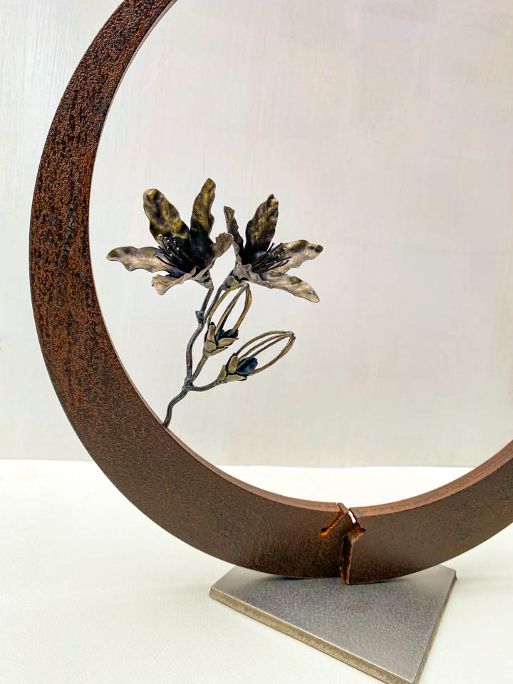 箱根の春を彩るミツバツツジの花を円弧に添えた鉄の彫刻、アート作品です。スタンドタイプです。蕾は鍛造した鉄線で表現し軽い印象になっています。円弧は厚みのある鉄を切り出し、下部でズラして表情をつけています。花の様子。