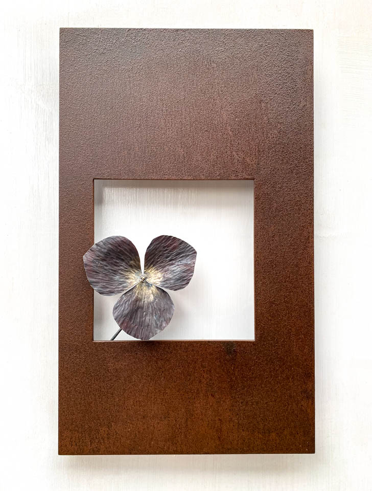 箱根に自制するエンレイソウの葉をモチーフにした鉄の彫刻、アート作品です。厚みのある鉄板に窓を開け、記号的なエンレイソウの葉が顔を出している、シンプルな構成です。葉の表面は丹念に鍛造しハンマートーンをはっきり付けて、中心部分を真鍮で磨き込み色味に変化をつけました。厚みのある鉄板は実際に錆びた風合いを残した仕上げとし、重厚な風合いを醸し出しています。