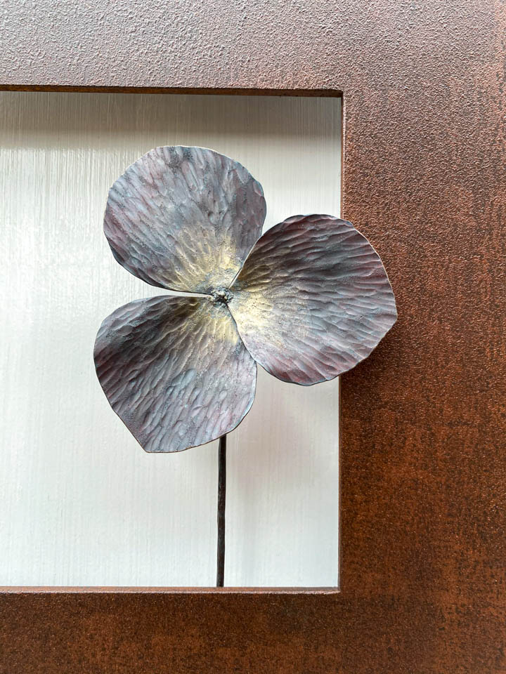 箱根に自制するエンレイソウの葉をモチーフにした鉄の彫刻、アート作品です。厚みのある鉄板に窓を開け、記号的なエンレイソウの葉が顔を出している、シンプルな構成です。葉の表面は丹念に鍛造しハンマートーンをはっきり付けて、中心部分を真鍮で磨き込み色味に変化をつけました。厚みのある鉄板は実際に錆びた風合いを残した仕上げとし、重厚な風合いを醸し出しています。