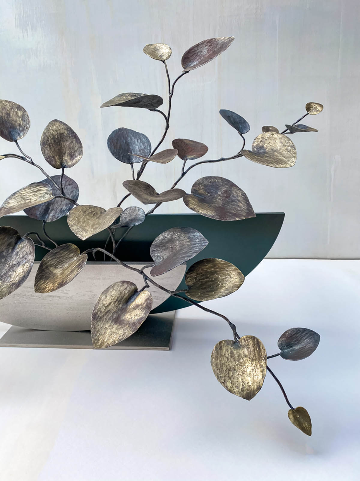カンガルーアイビーの軽やかな葉が空間に溢れる姿の鉄のアート作品。大小の葉がリズミカルに展開します。葉の素材は全て鉄で、磨き仕上げの違いで色味を変えています。ベースから広がる葉の様子。