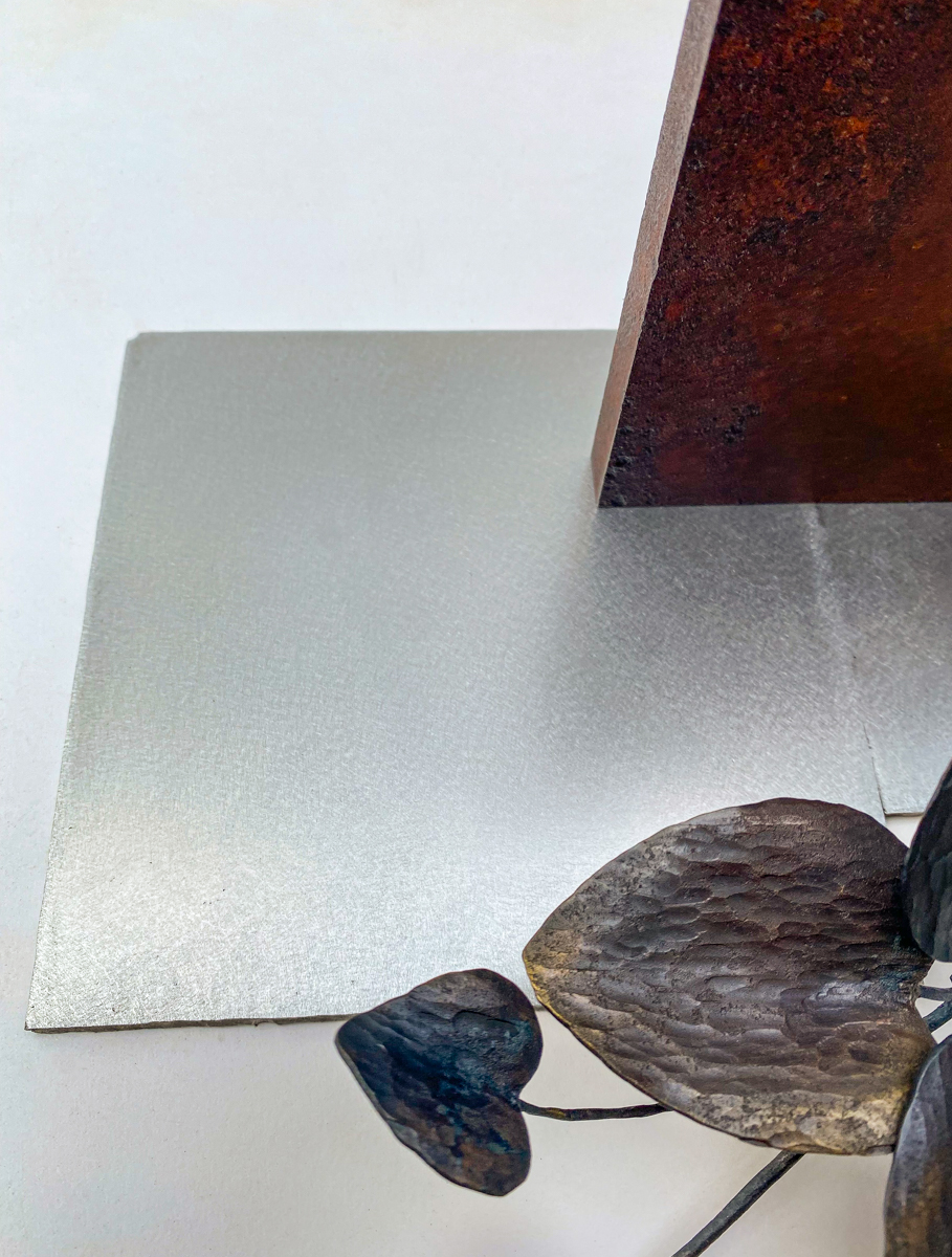 丸い開口が連なる表情豊かな鉄の厚板に、カンガルーアイビーのツルが肩から下がるよう配置した鉄のアート作品です。華やかな大小の葉がリズミカルに連なり、軽やかな印象の彫刻作品になっています。葉の表情。ベースのステンレス板の表情。