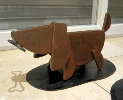 笑顔の口元の形でもある、半円形を集めて作った犬のアート彫刻。骨をくわえています。