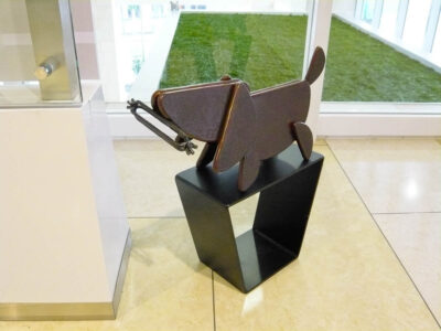 笑顔の口元の形でもある、半円形を集めて作った犬のアート彫刻。ソーセージをくわえています