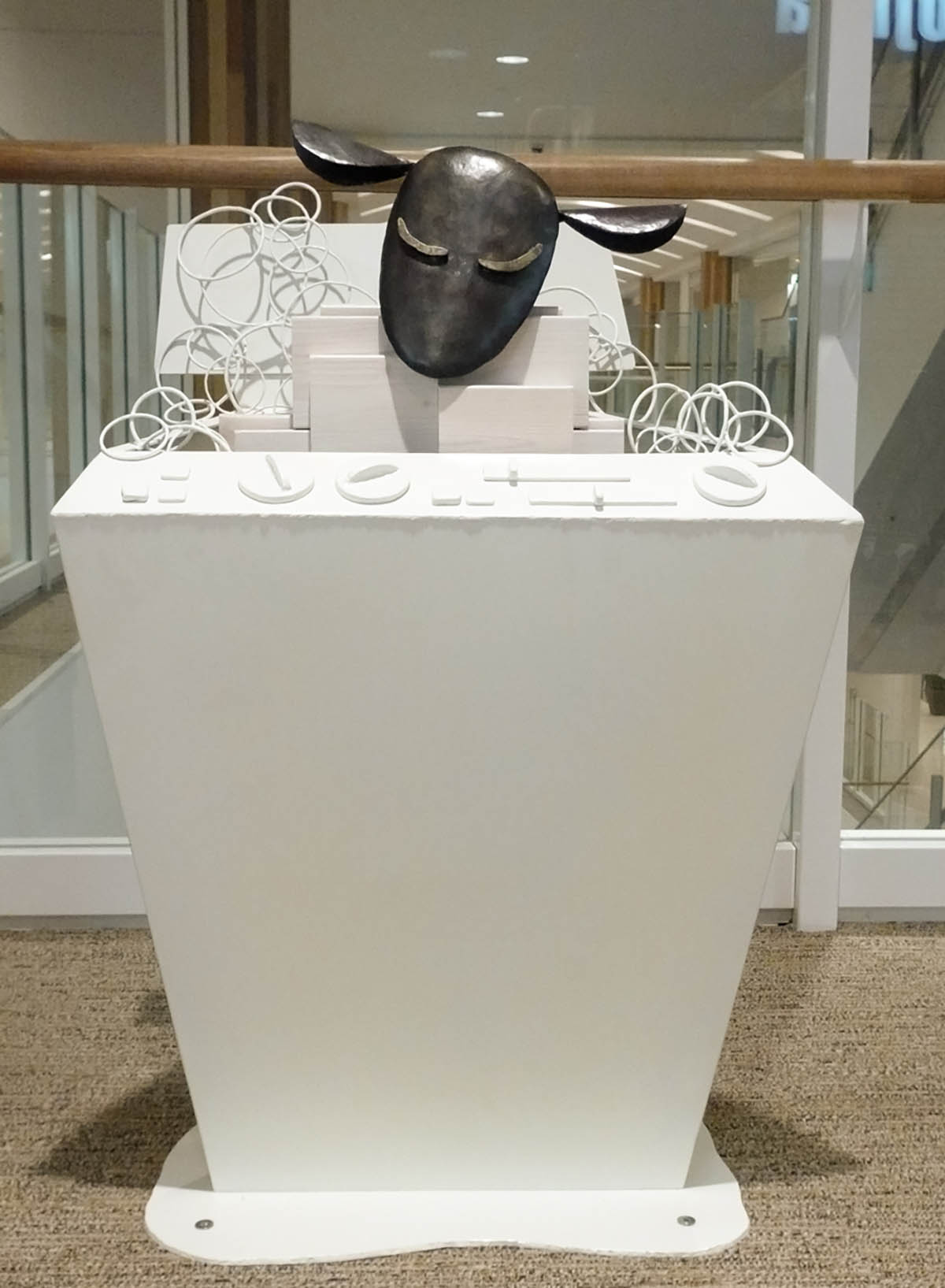 木と鉄で創られた羊のオブジェ彫刻。洗濯機で洗濯される様子。洗濯機は旧式で、泡まみれで浸かっています。