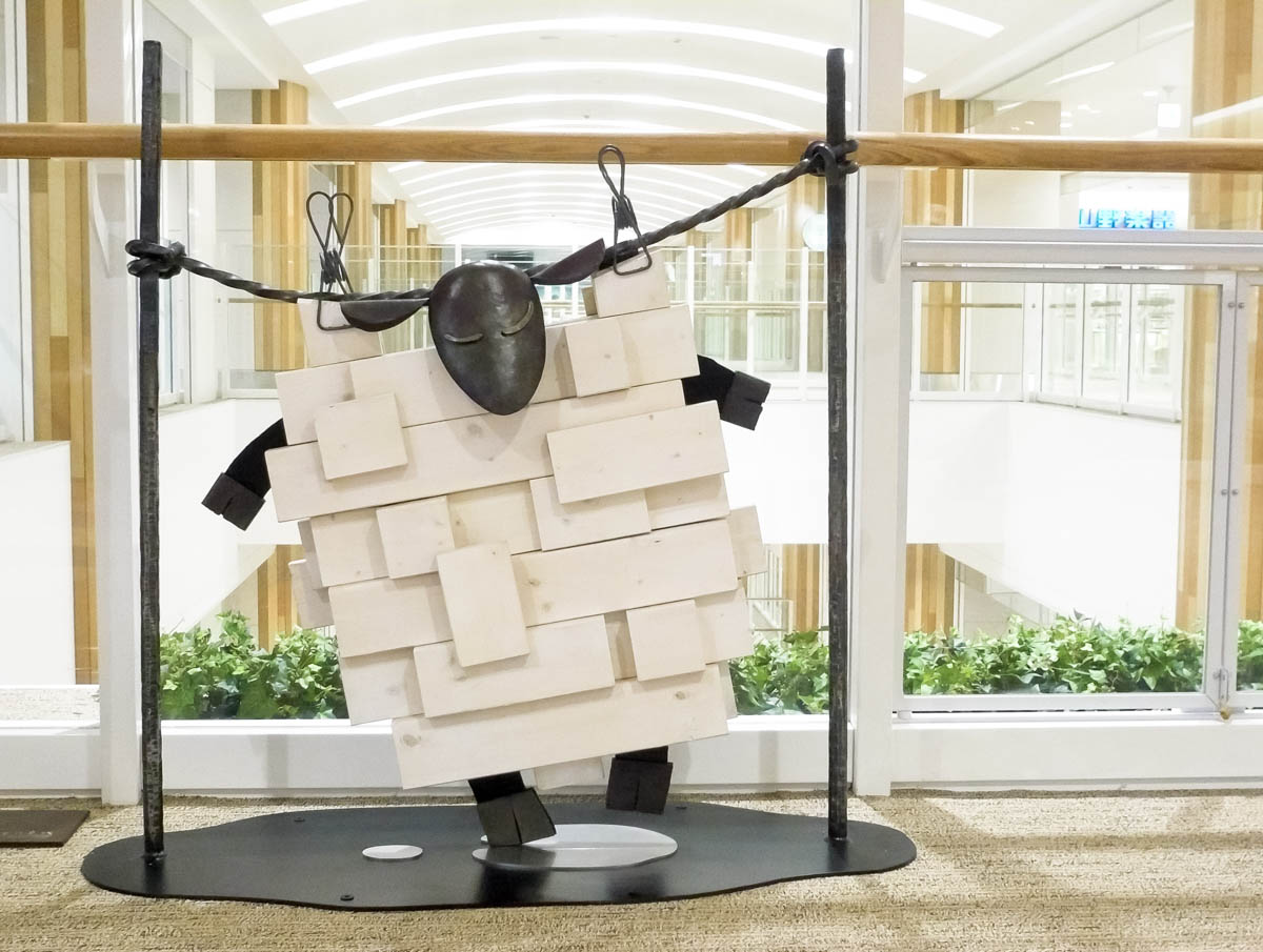 木と鉄で創られた羊のオブジェ彫刻。洗濯された羊が吊るされて干されている様子。